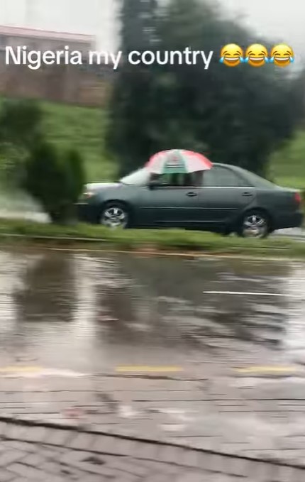 "The glass no fit wind up be that" – Driver refuses to close car window, opts for umbrella in heavy rain (VIDEO)